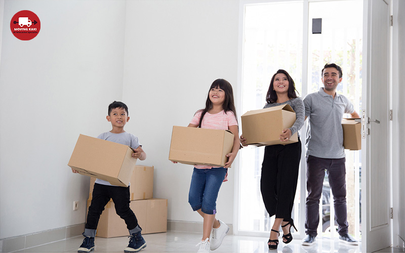 happy family holding boxes going inside the house